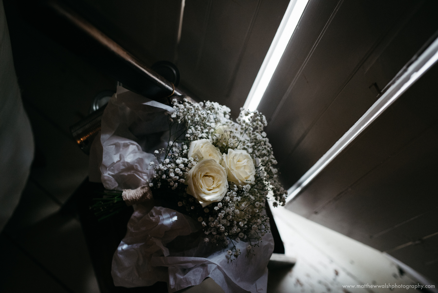 The brides bouquet also lit by a slither of light coming in through the french doors in the drawing room