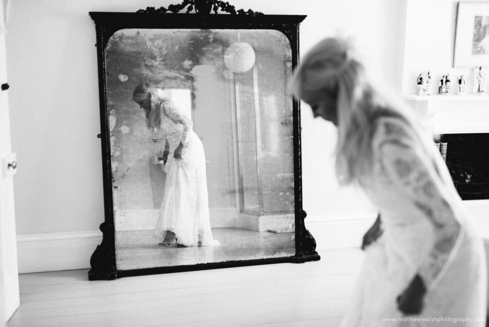 The bride checks her dress in the mirror in the bridal suite at Lyde Court wedding venue