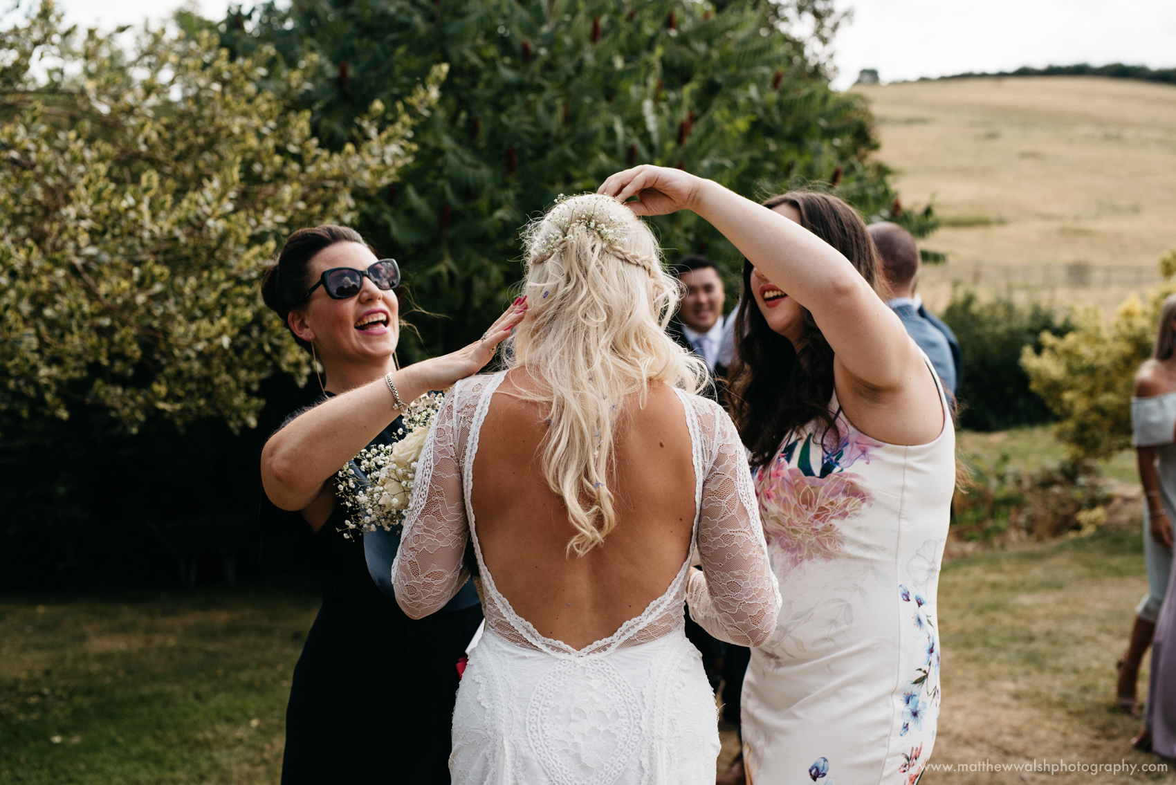 Friends of the bride help remove confetti from her hair