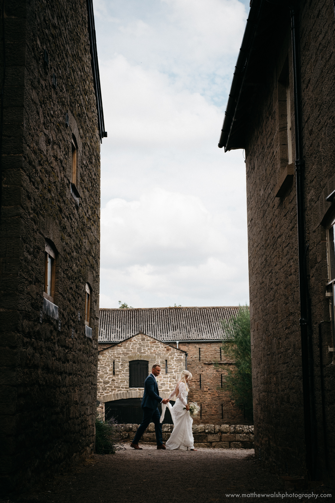The bride and groom walking in the light, using the buildings and shadows to frame them