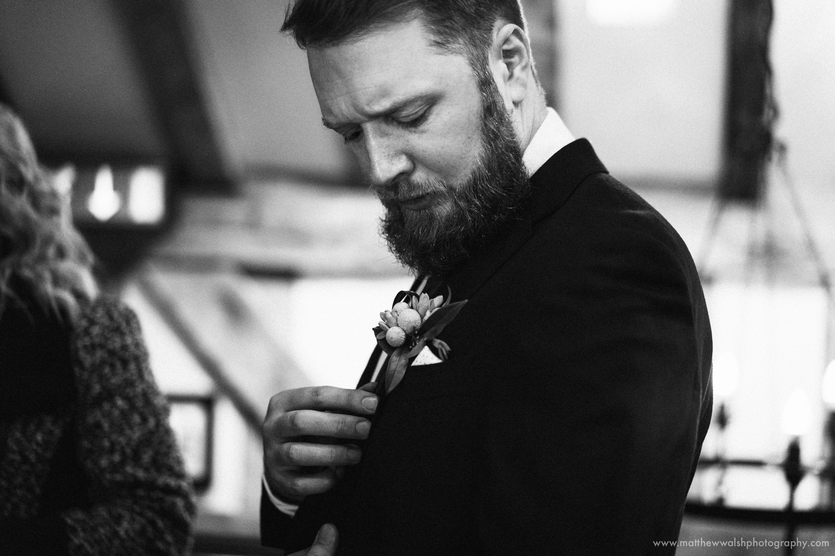 The Groom adjusts his buttonhole flower having just put it on