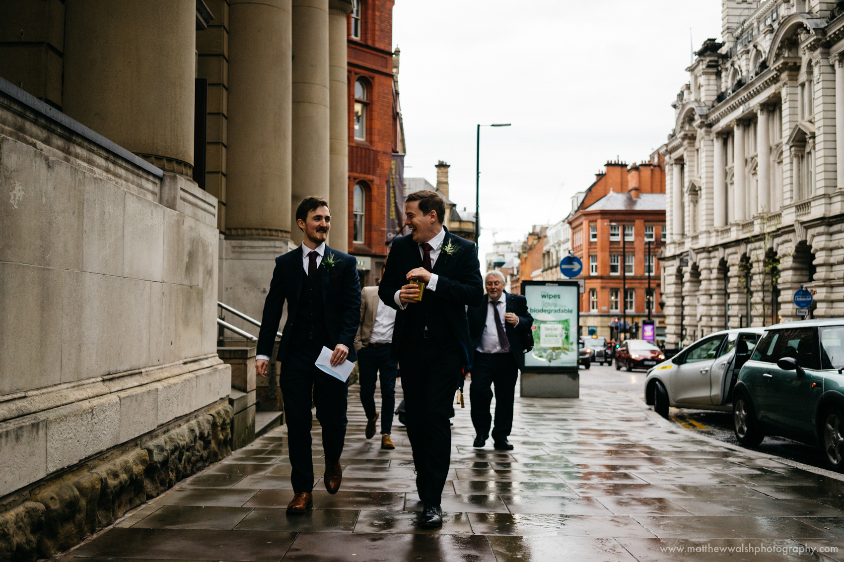 The best man and groom share a wee tipple from a hip flask on their walk from the ceremony  to the bar and restaurant