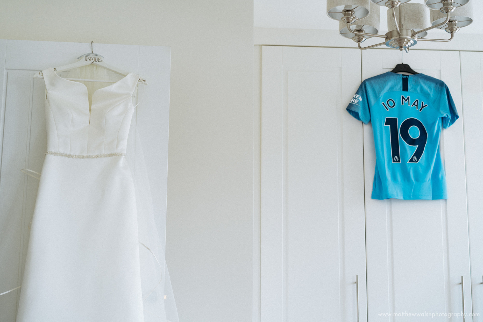 The wedding dress hanging bu a Manchester City football shirt with the wedding date on, the bride being a big football fan