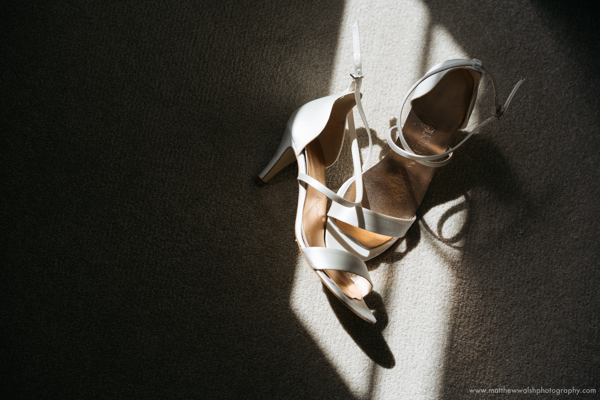 The brides shoes sitting in a pocket of natural sunlight