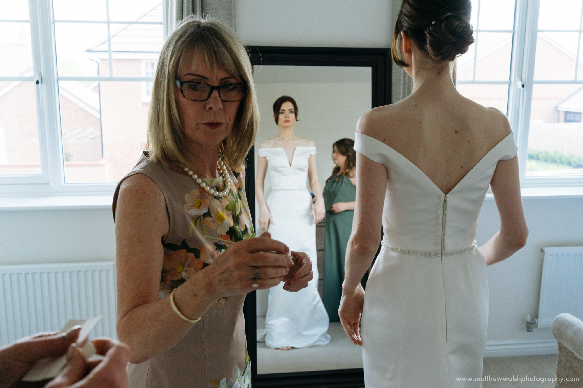 The mother of the bride helps her daughter to put her dress on in keeping with tradition 