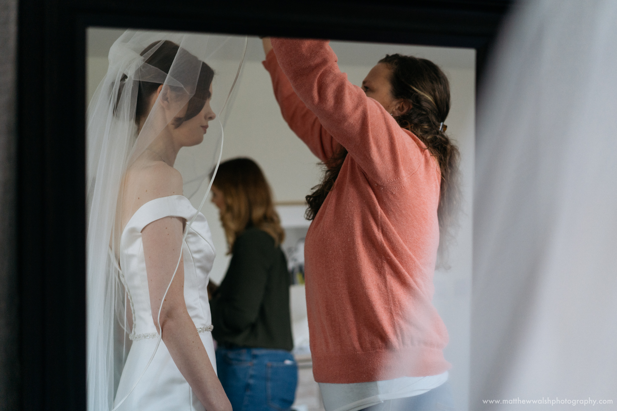 The hair stylist helping the bride with her veil