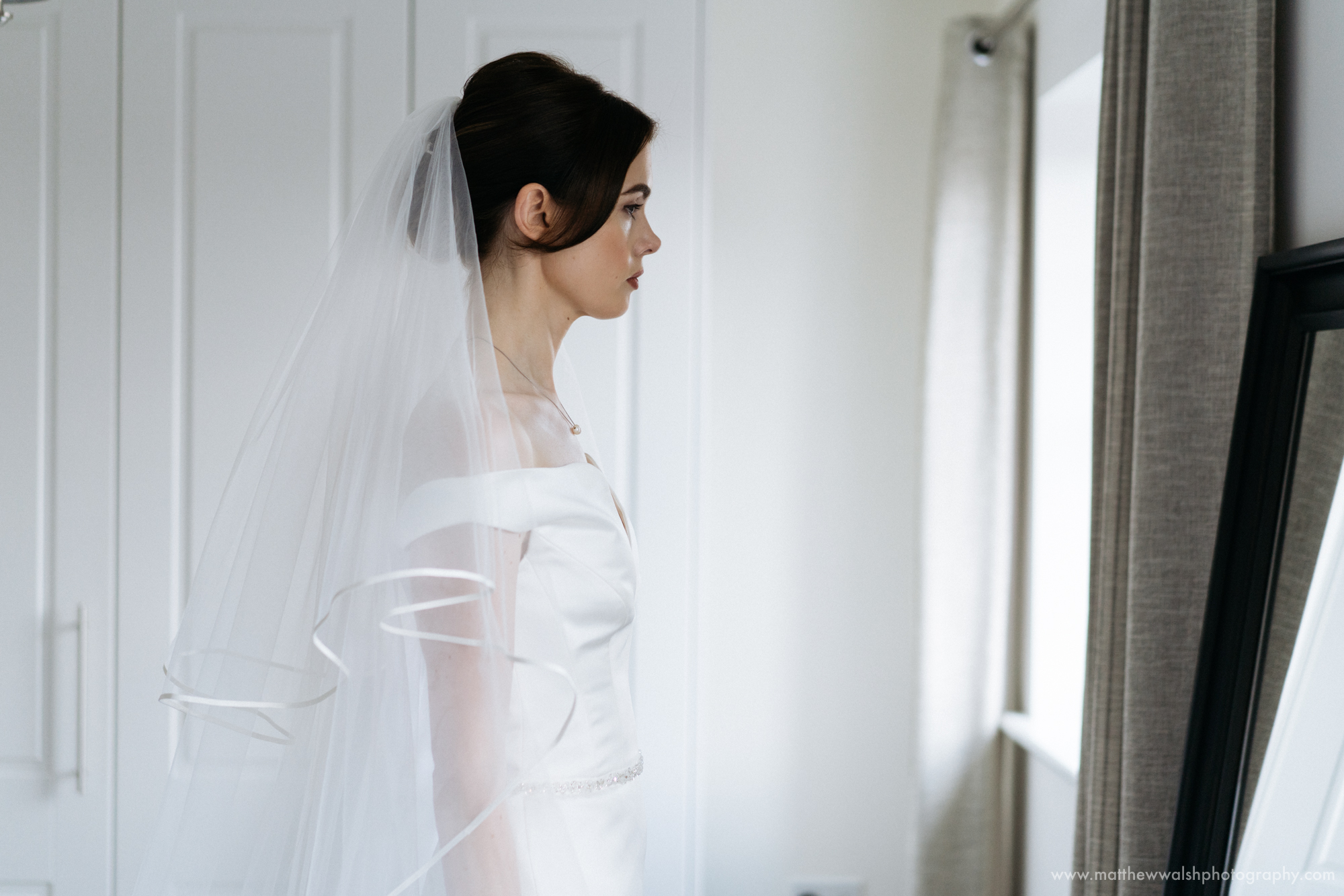 A colour image of the bride looking at herself in the mirror