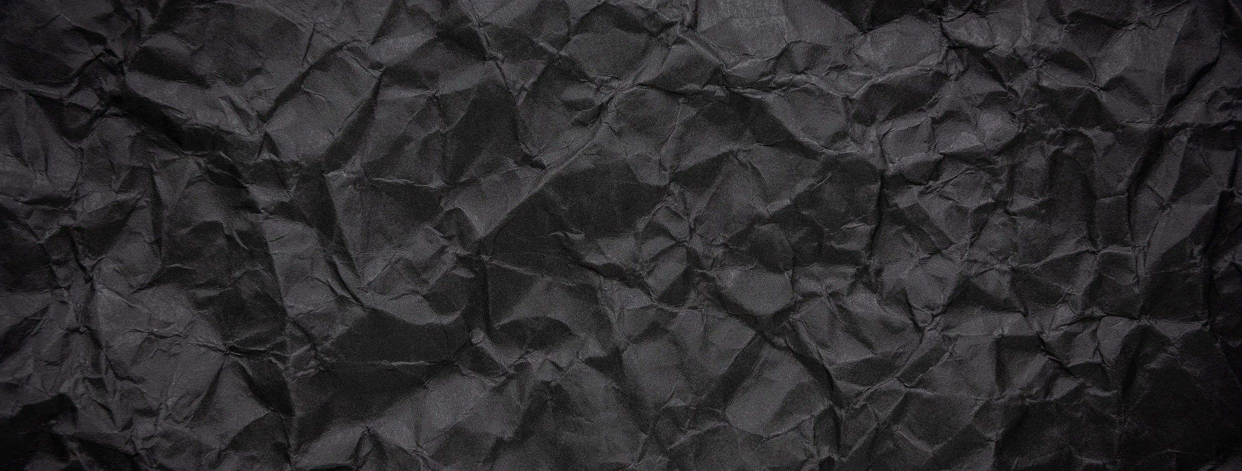Ragged crumpled dark black paper texture background