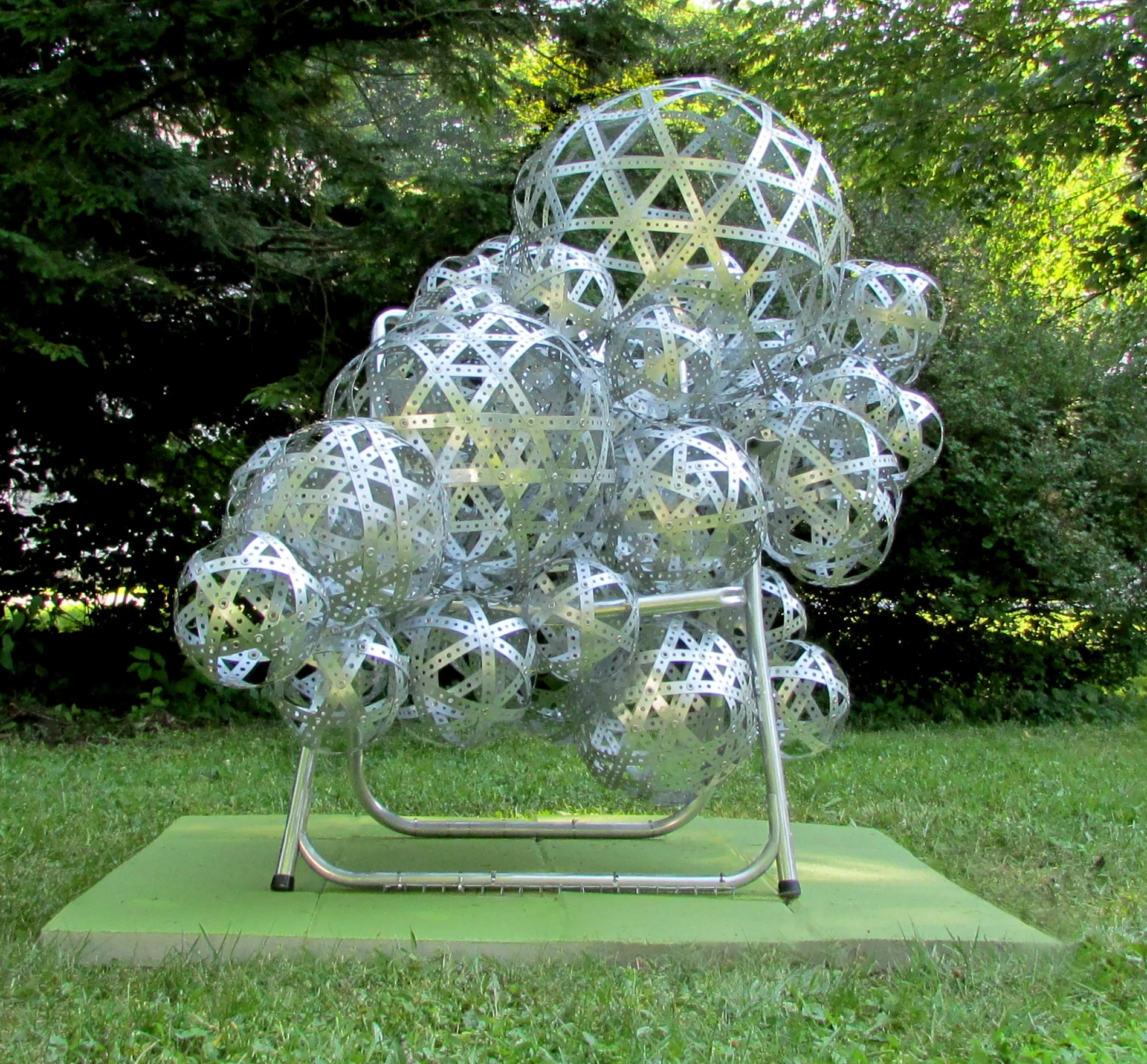 “Guest/Host” (2018) Front view.. 45”W x 65”D x 56”H, Perforated metal strapping, aluminum lawn chair frame, grommets.