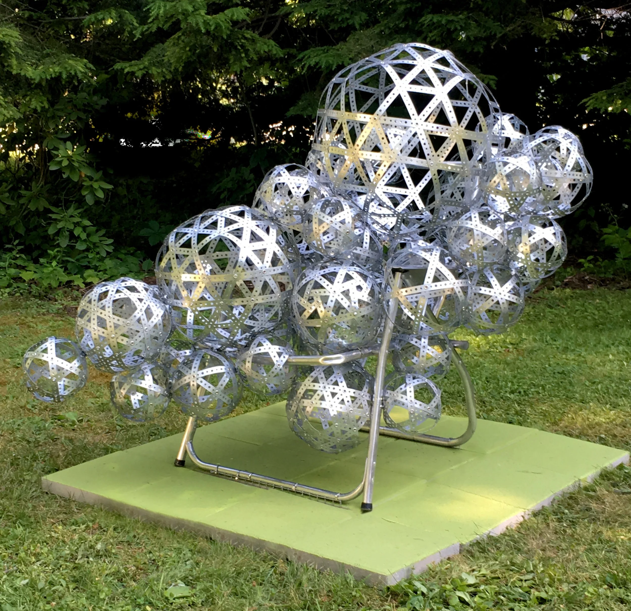 “Guest/Host” (2018) Front right. 45”W x 65”D x 56”H, Perforated metal strapping, aluminum lawn chair frame, grommets.
