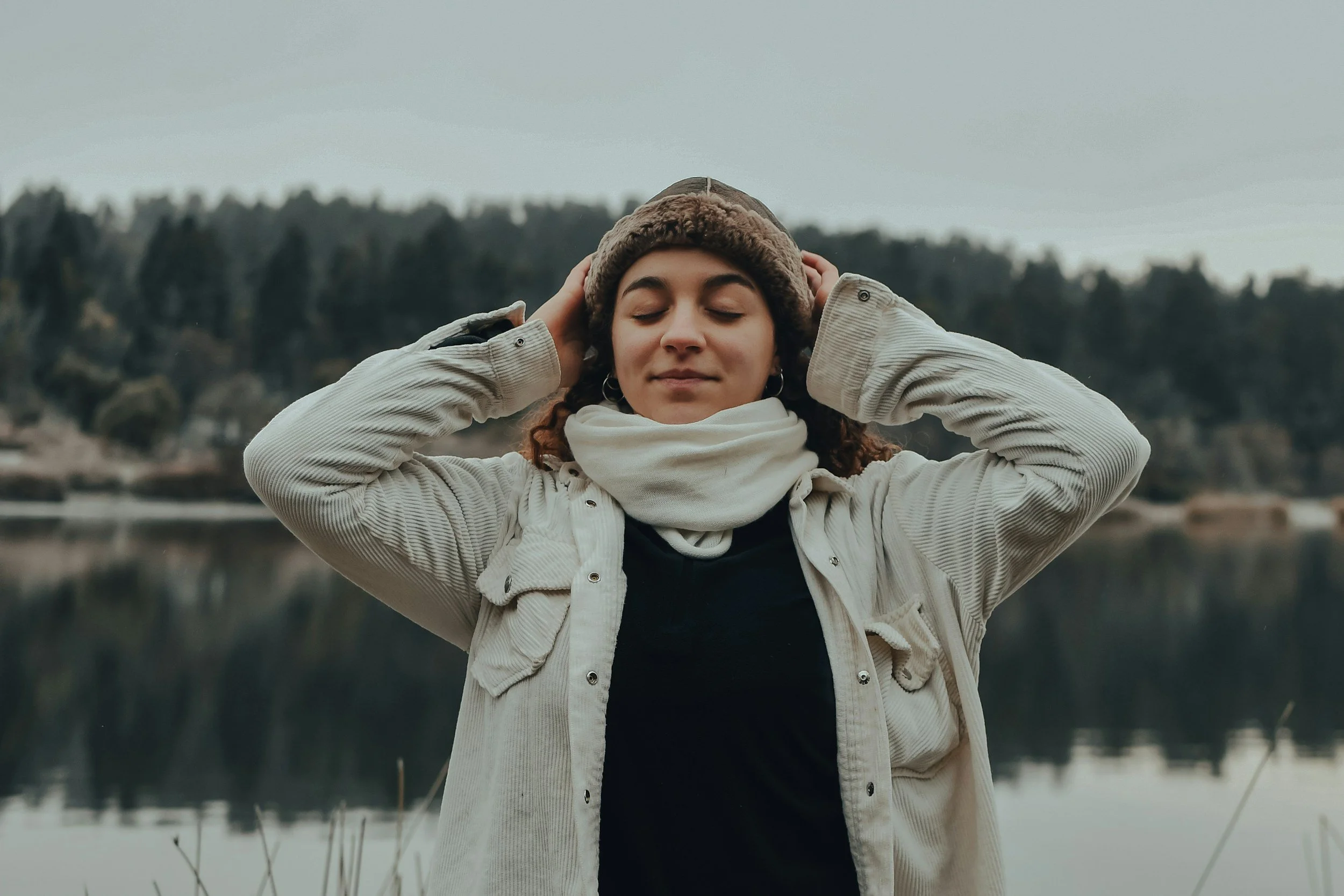 A woman is outside and looks peaceful. Therapy for imposter syndrome can help people trust themselves more and feel more present in their lives.