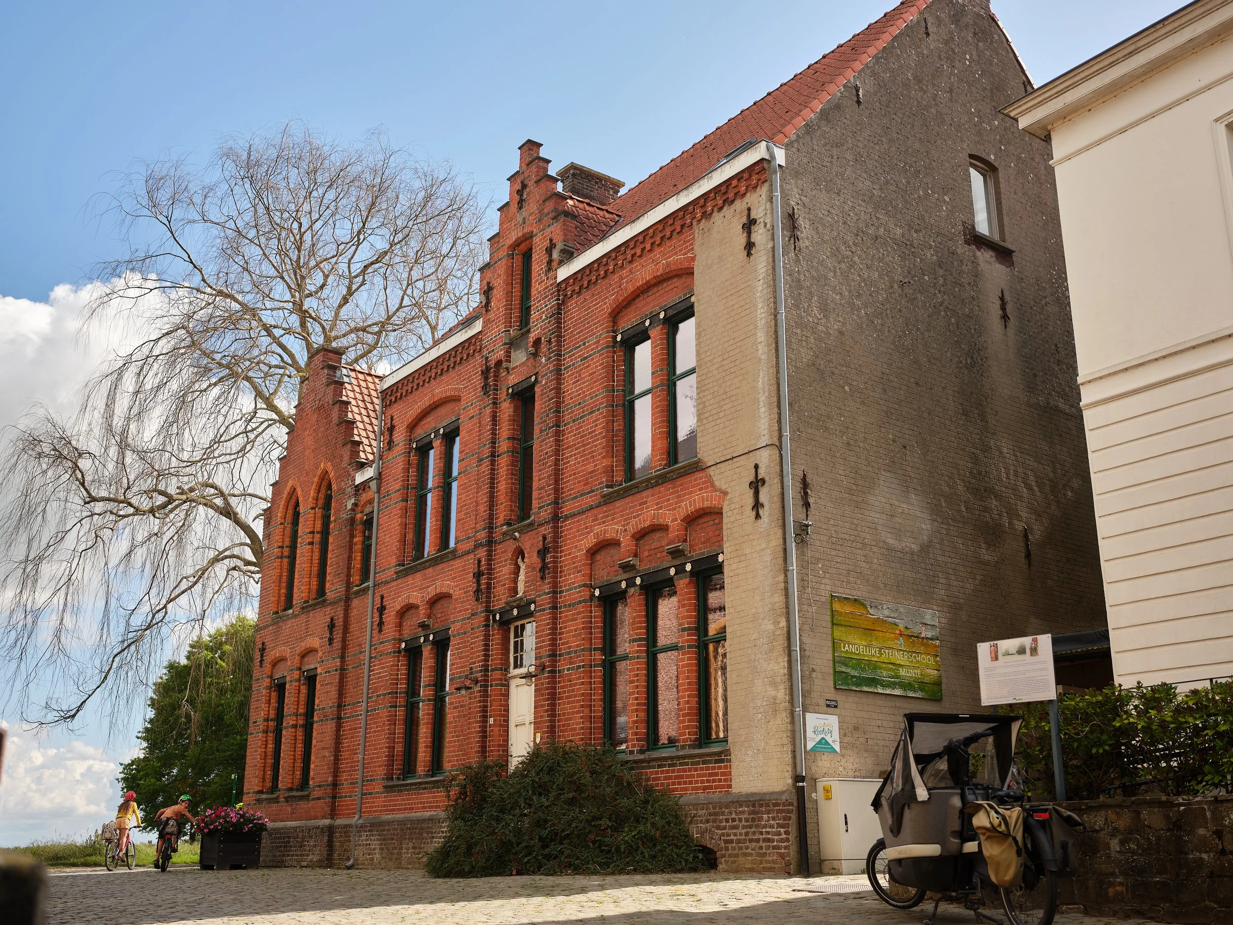Het leek een draak die zich niet temmen liet. Ach domme draak,
vergist u niet !
Na jarenlang vrij spel,
vervangen wij die ramen w&eacute;l !
En ziet de schoolgevel nu eens blinken,
groen houtwerk laat onze ziel vrolijk klinken.
Ons hart vervuld van d