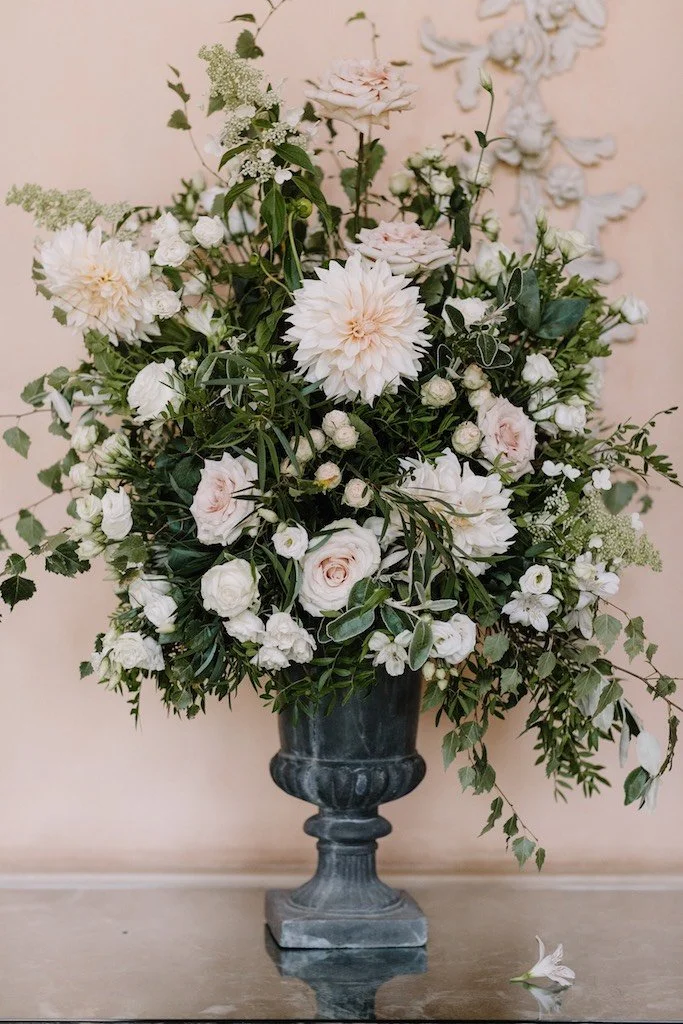 A stone urn full of green foliage with white and blush flowers at Kelmarsh Hall