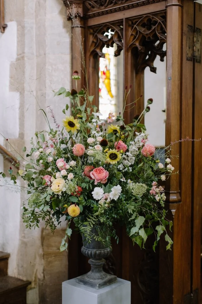 Large urn filled with colourful meadow style flowers by The Flower Story