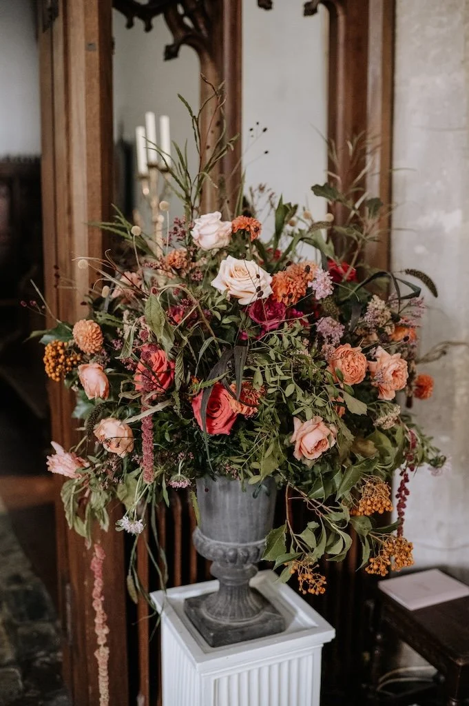 Stone urn filled with colourful wedding flowers in St Marys Chich