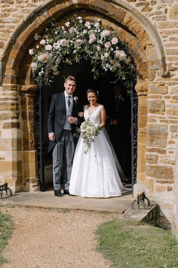 A floral wedding arch outside church door