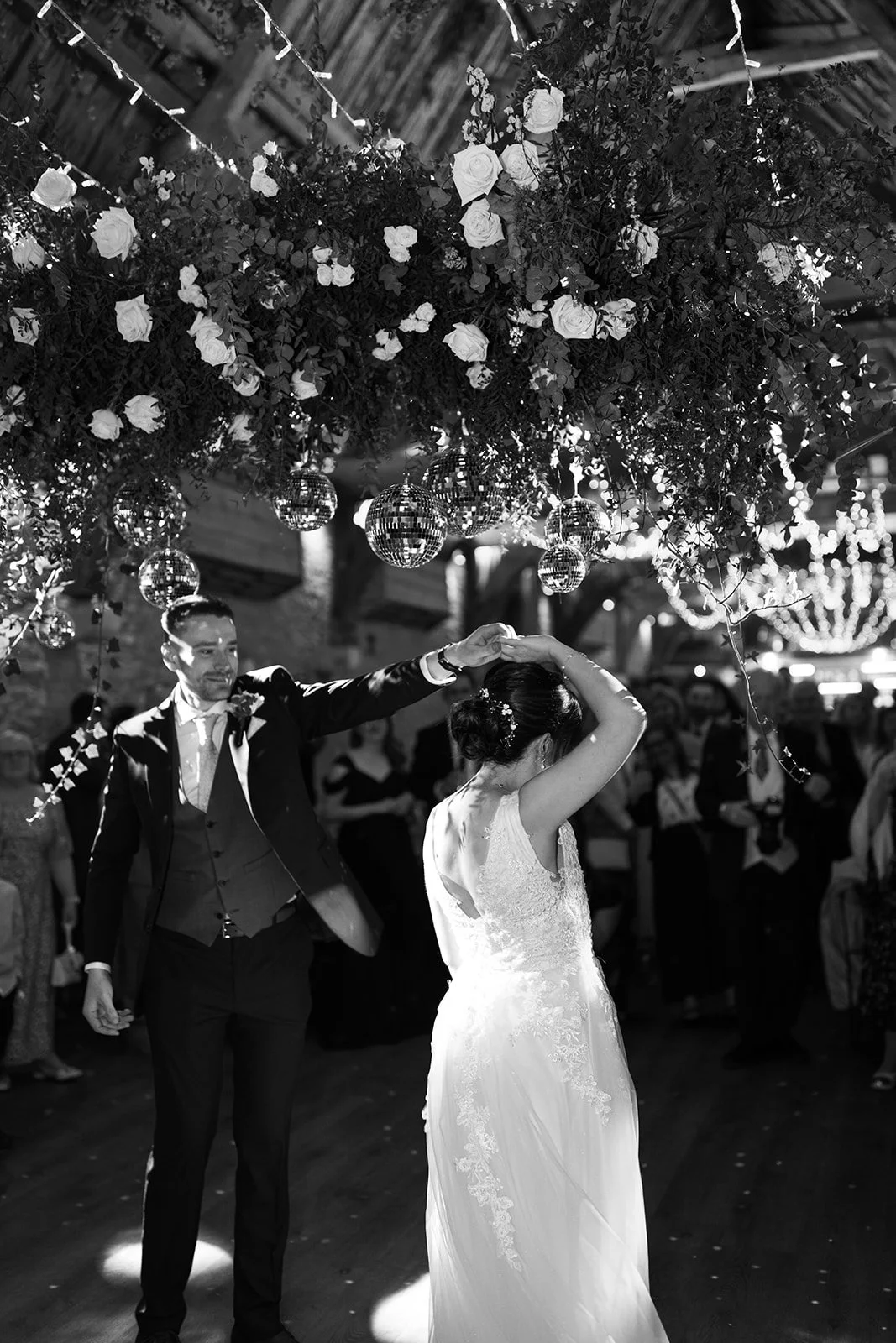 Just married couple dancing under a flower and glitter ball arch