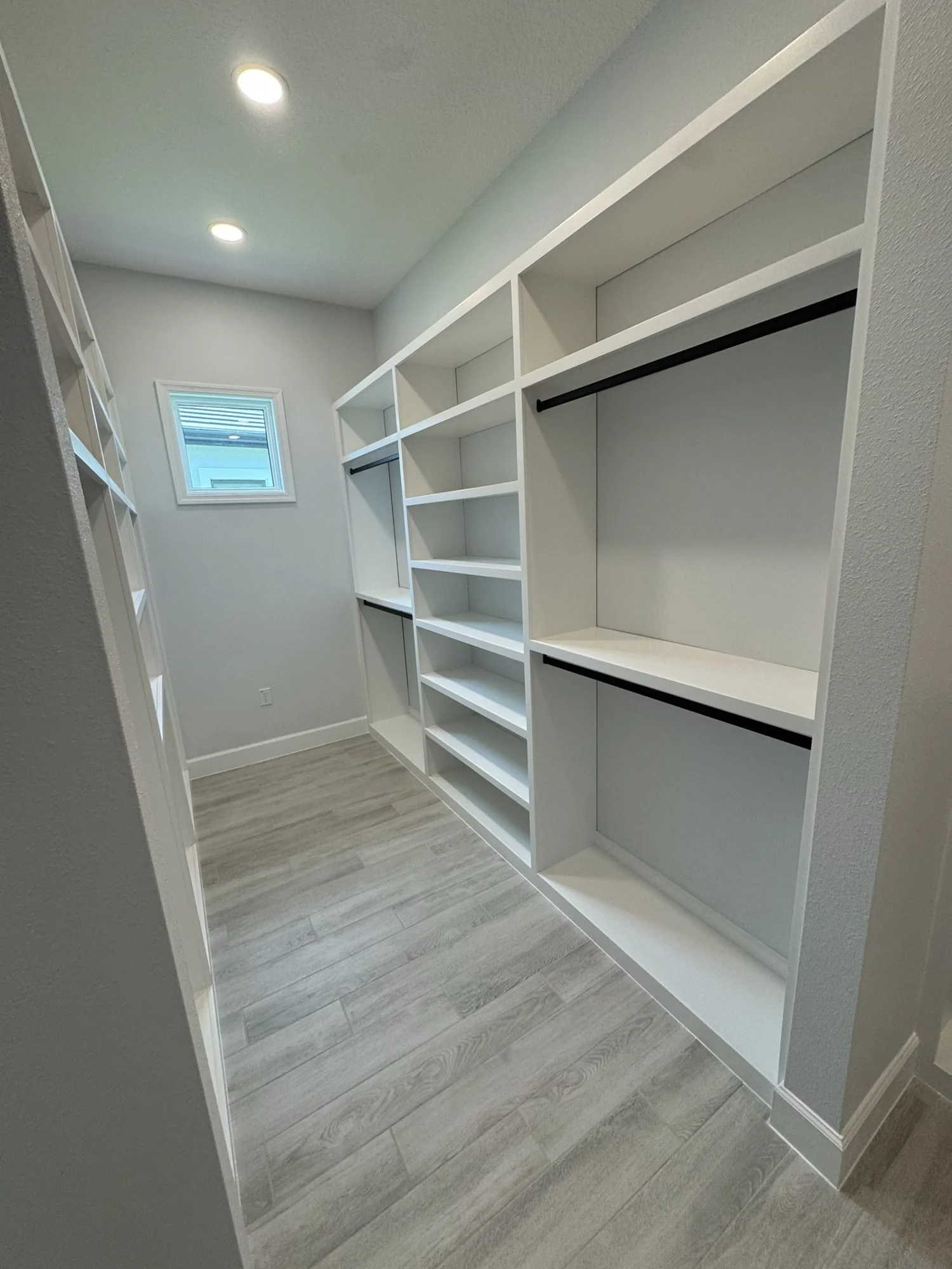 Walk-in closet with white built-in shelving and hanging rods