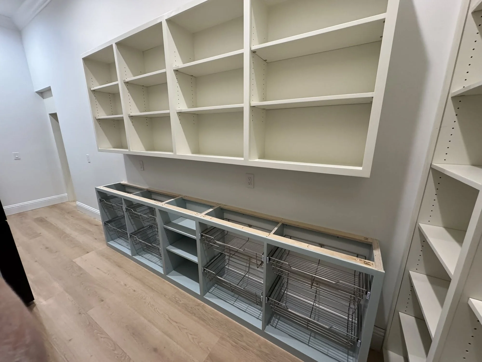 Pantry wall of open shelves over basket base cabinets