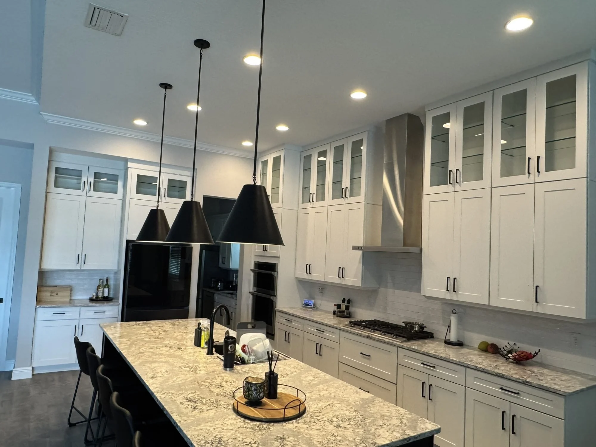 White shaker kitchen cabinets with glass-front uppers and granite island