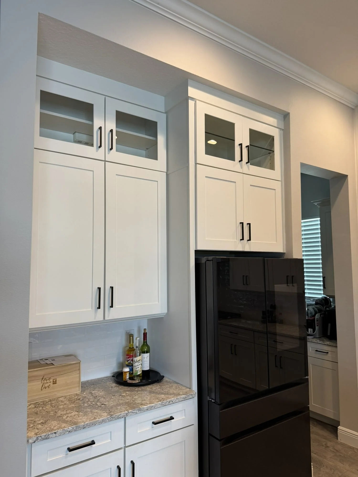 White kitchen cabinets with glass-front uppers around the refrigerator