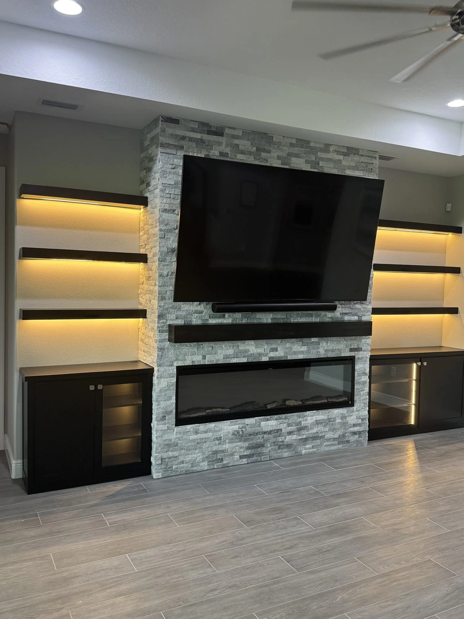 Fireplace wall with mantel, electric fireplace and lit floating shelves