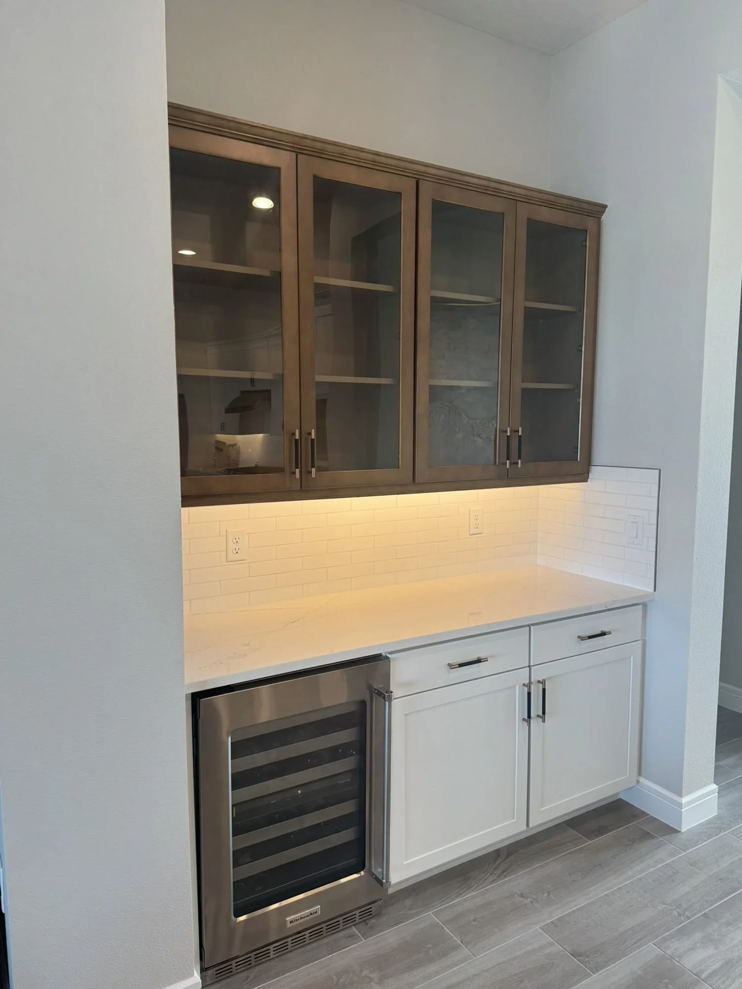 Dry bar with glass-front upper cabinets, angled view