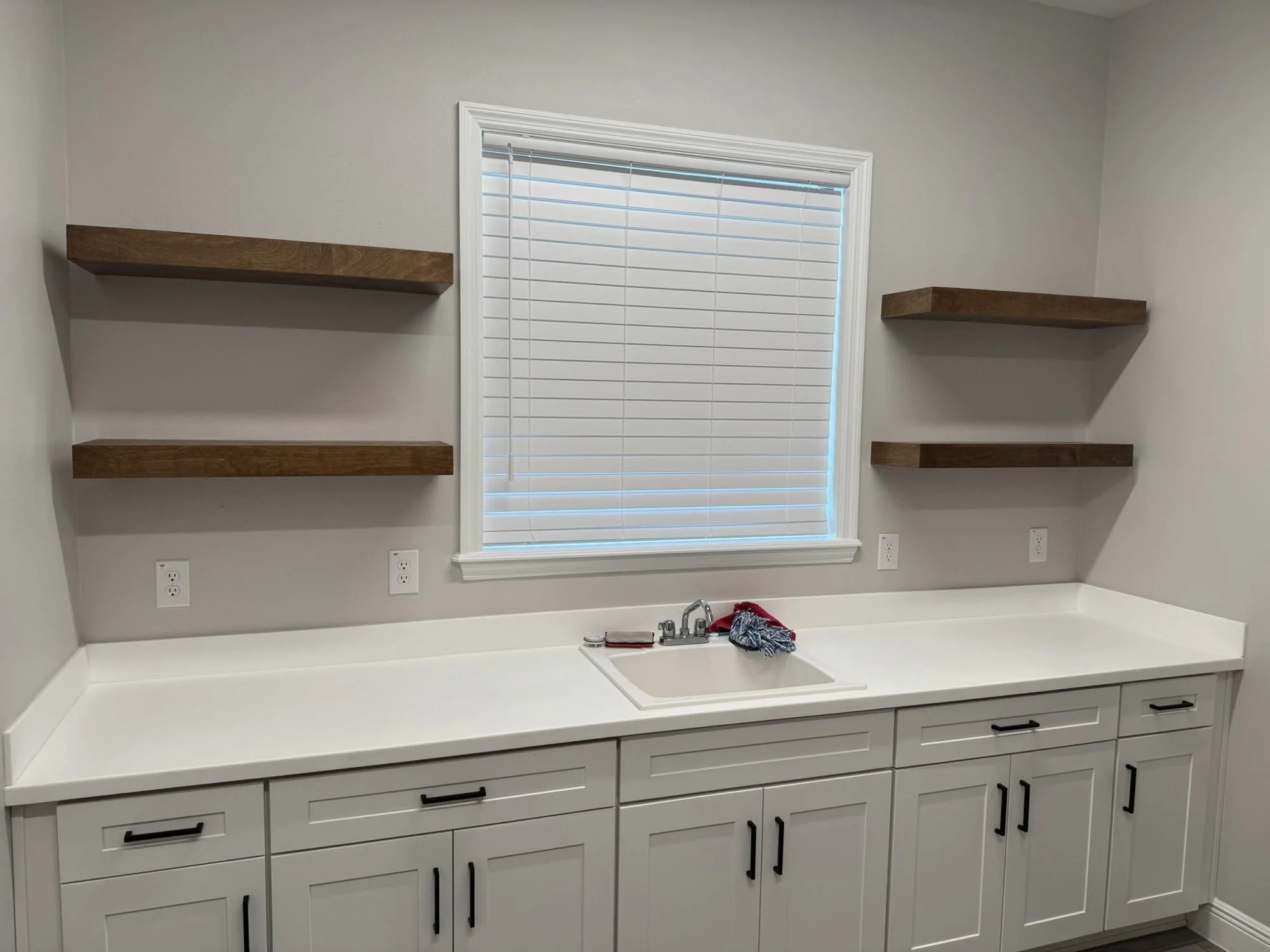 Built-in cabinets with quartz top and floating shelves around a window