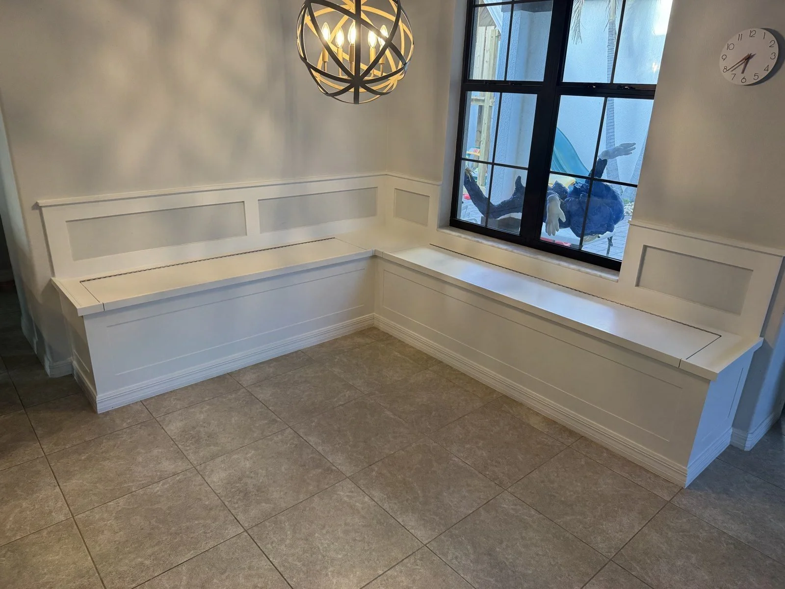 White L-shaped built-in banquette bench in a breakfast nook