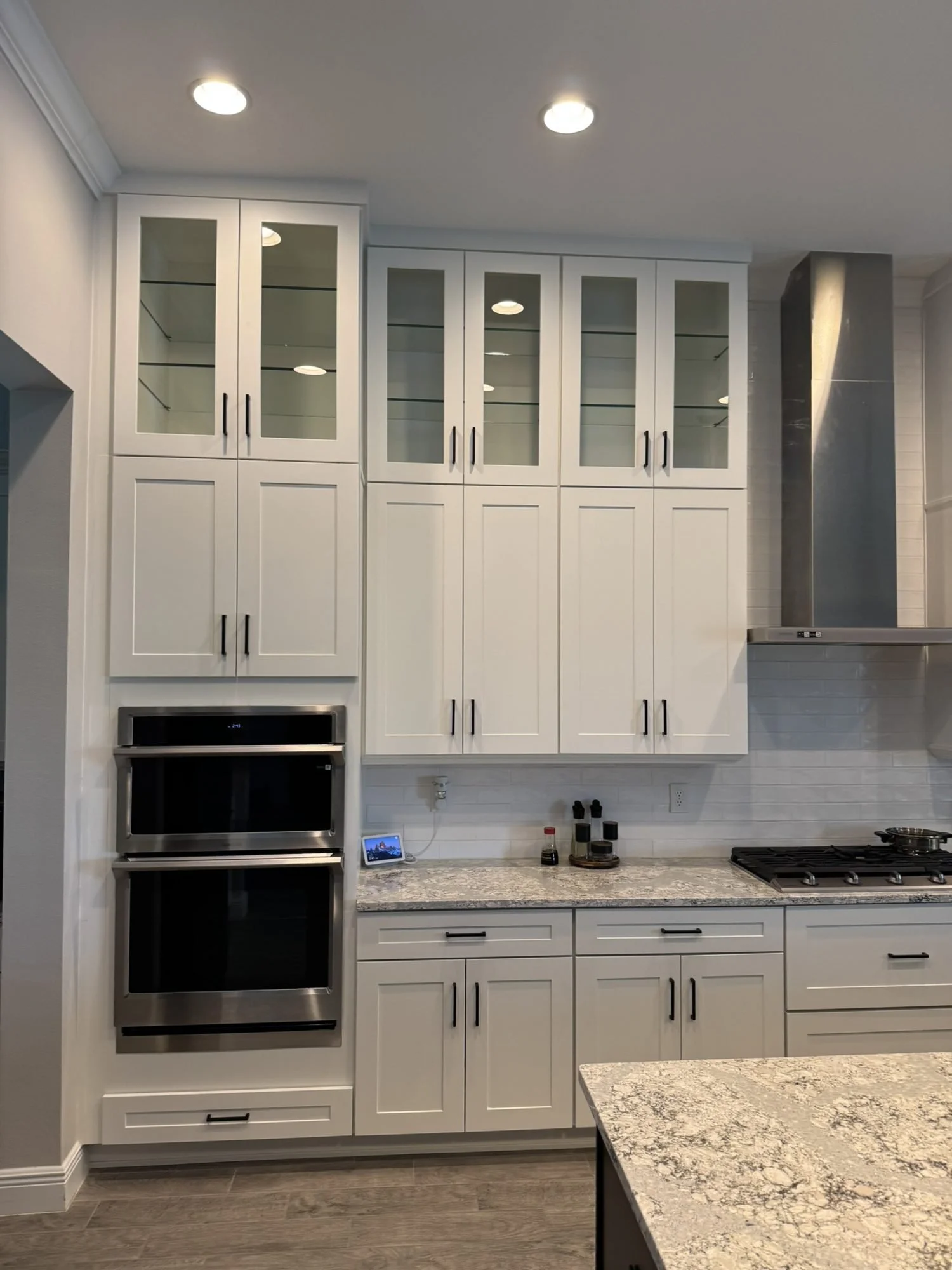 Tall white kitchen cabinets with double wall oven and range hood