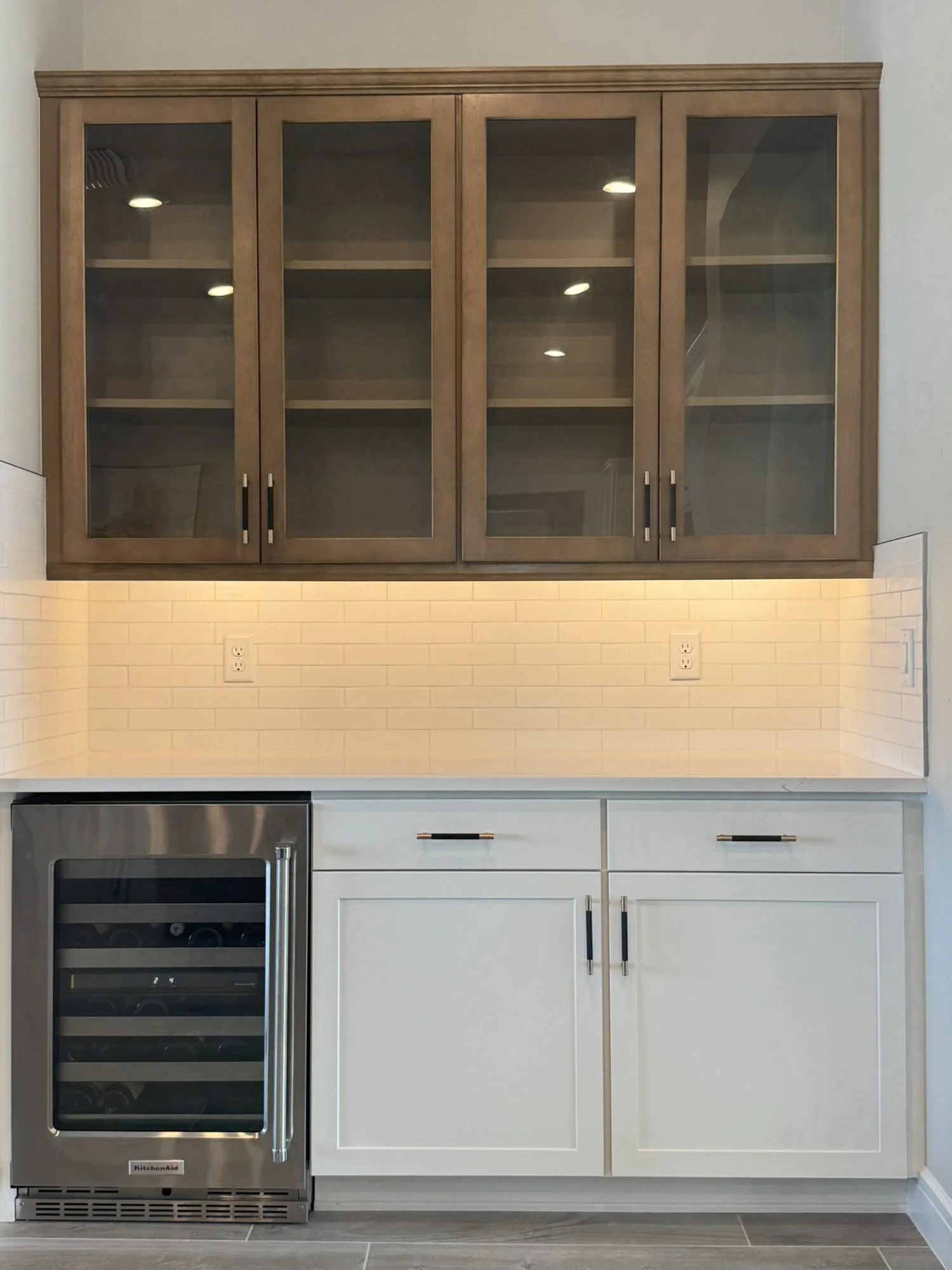 Dry bar with stained glass-front uppers, white base cabinets and wine fridge