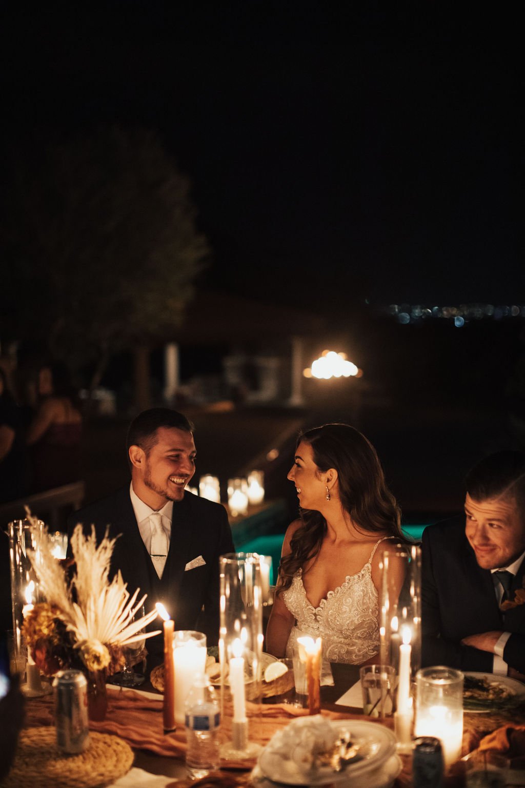 bride and groom low light at dinner looking at each other smiling