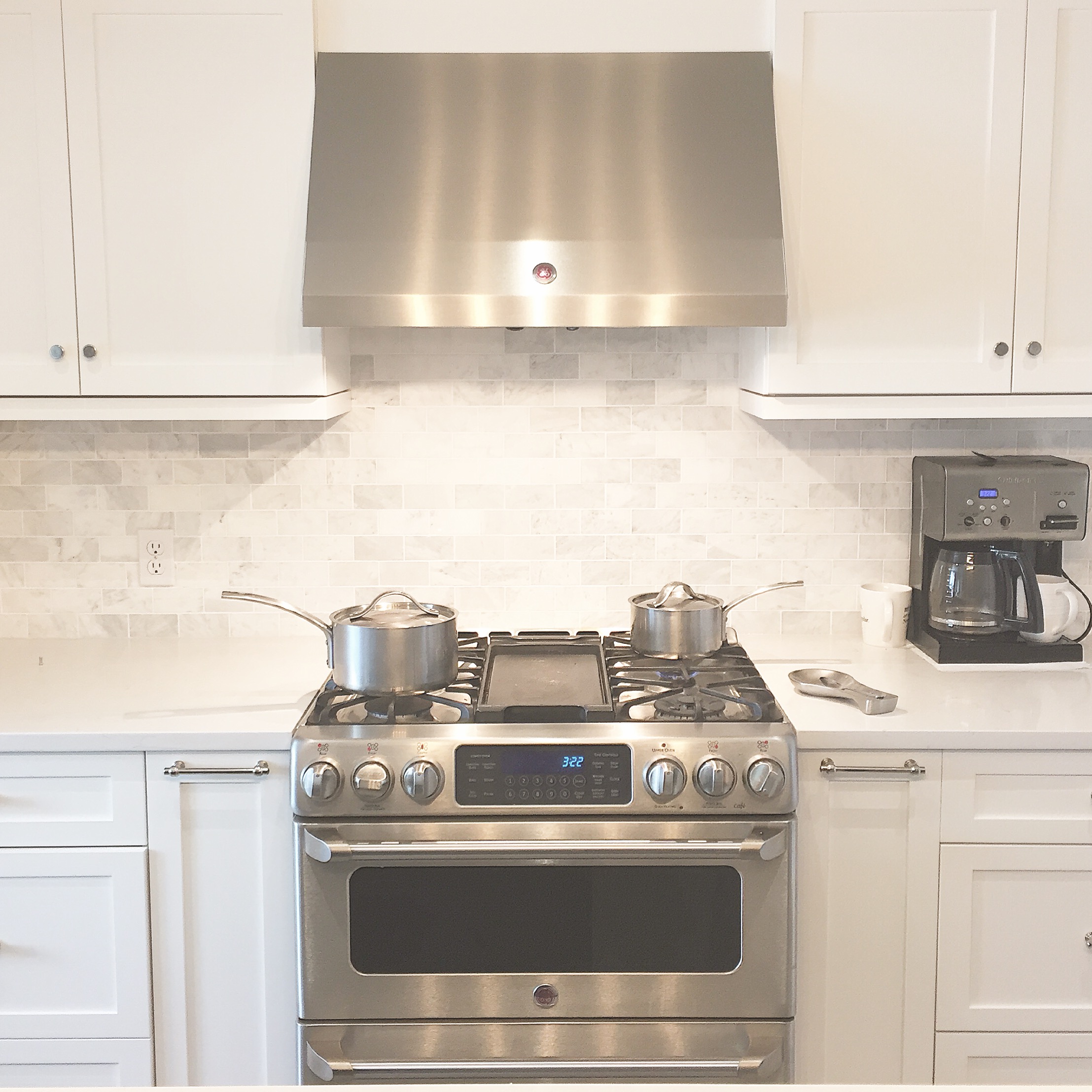 Simple white kitchen with identical cabinets on either side of the range. 