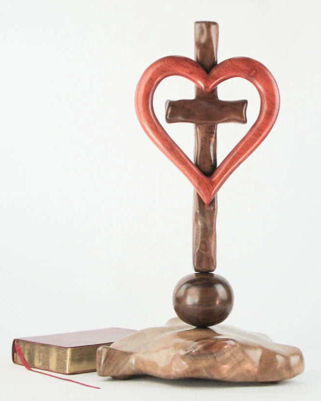 A decorative sculpture of a cross with a heart, an orb and a beautiful base