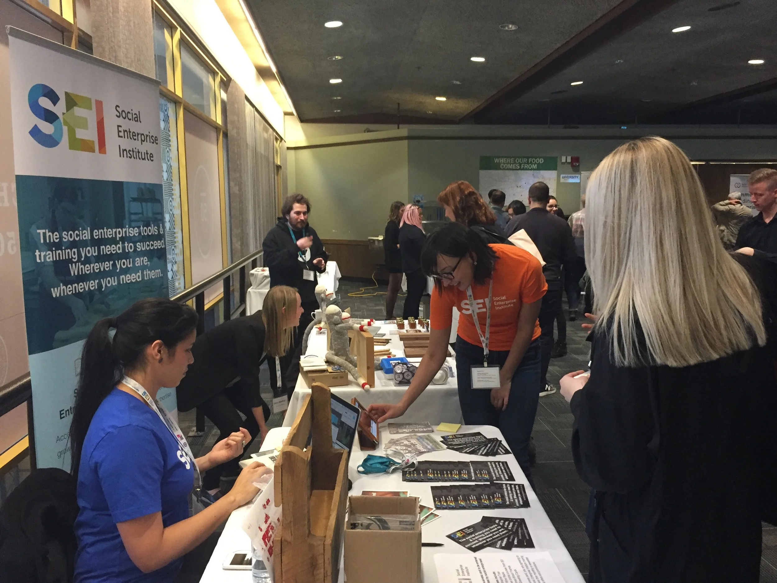 Common Good Solutions' SEI Learning Management System Coordinator, Stephanie Pronk (Right, Orange) and Business Development Office Lauren Sears (Left, Blue), signing up new SEI learners at the Canadian Conference on Social Enterprise.