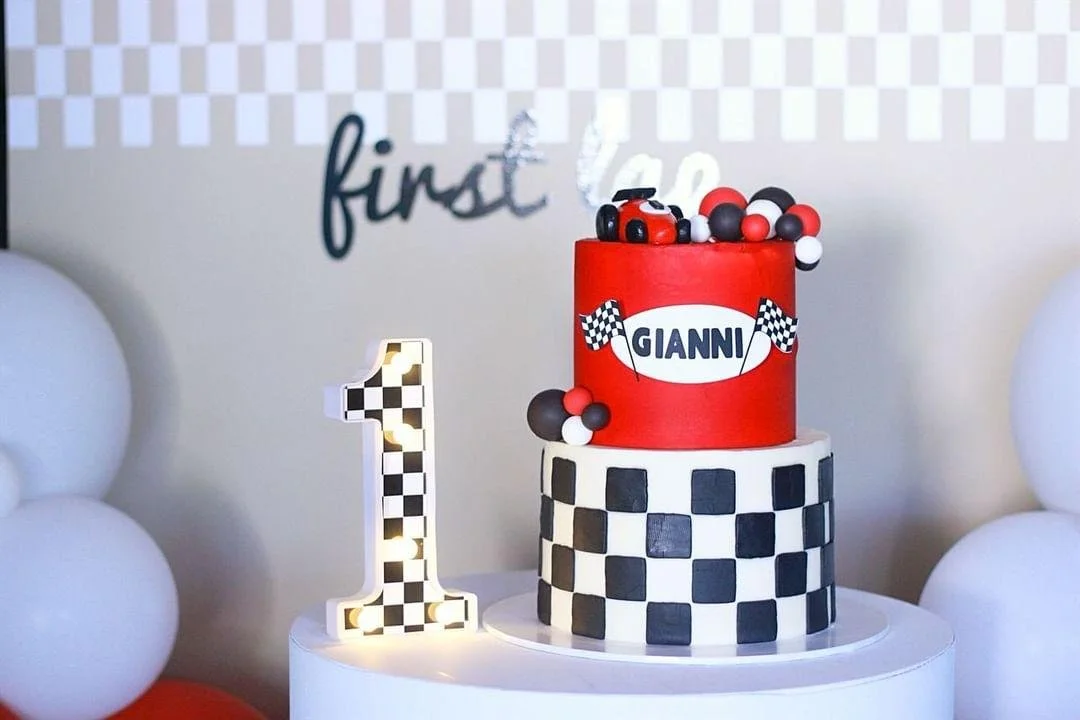 two tier round birthday cake with fondant formula 1 racing car on top, black, red, and white color scheme
