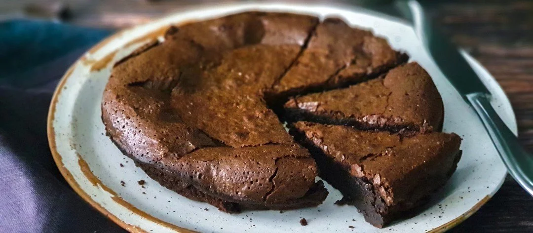 Slice of rich low FODMAP flourless chocolate cake on a dessert plate.