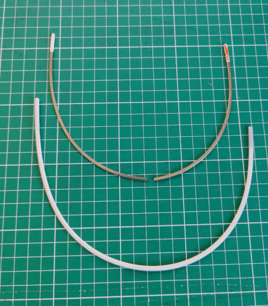 Two bra wires on a cutting mat, one of them is snapped