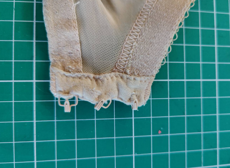 A close up of the hooks part of a bra, they are badly damaged and trying to escape the fabric