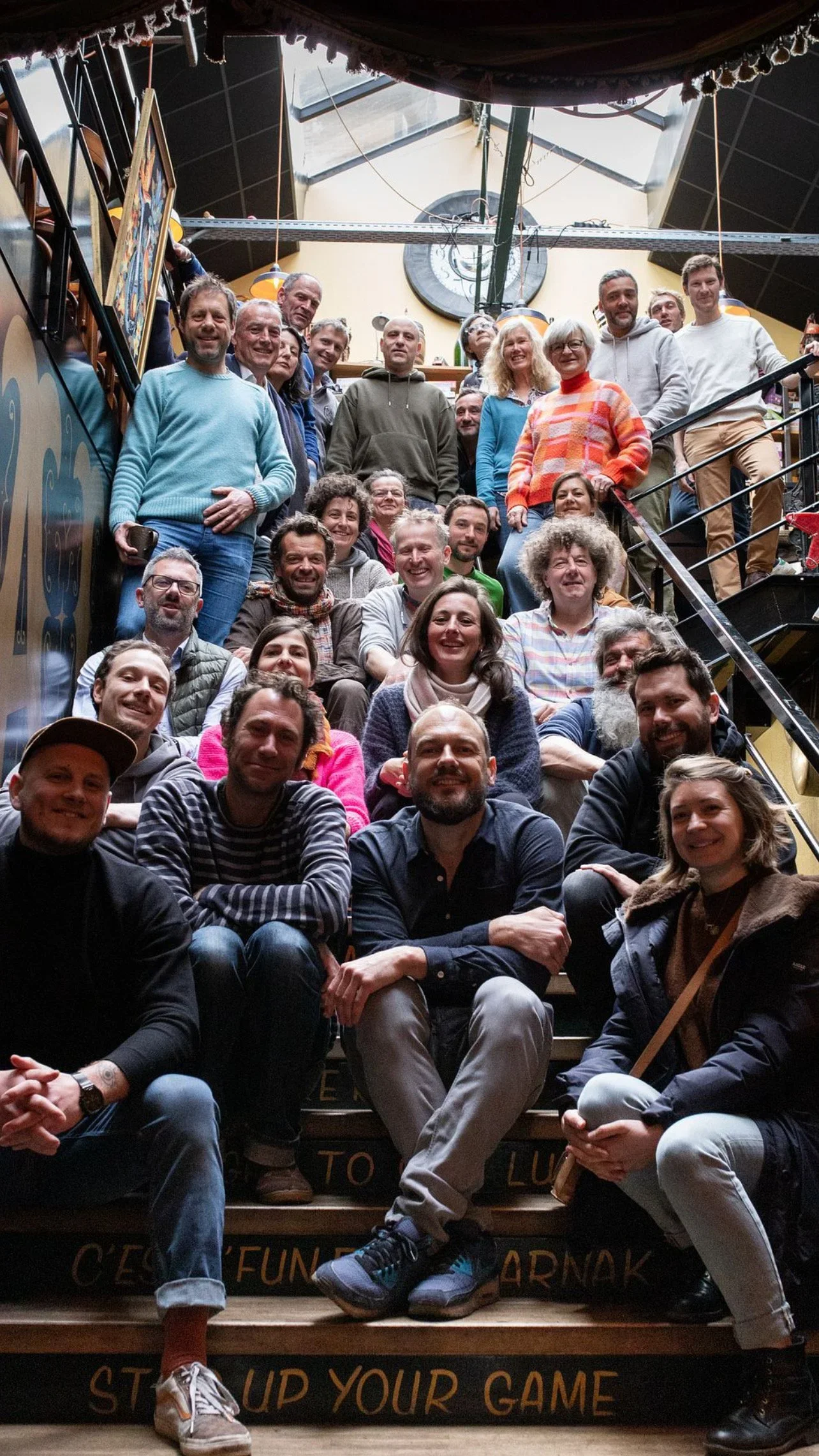 Groupe de personnes posant sur un escalier à l'intérieur d'un bâtiment, souriantes et détendues.