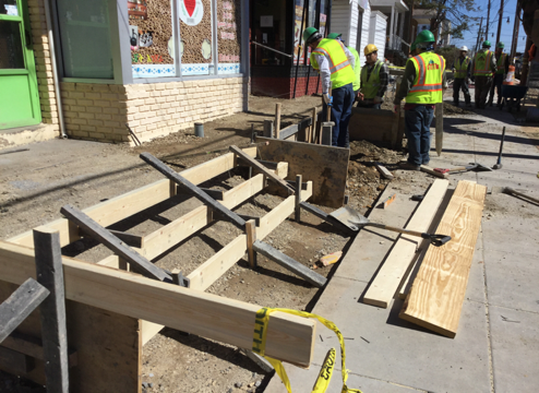 Contractor placing forms for ADA ramps and stairs leading to businesses.