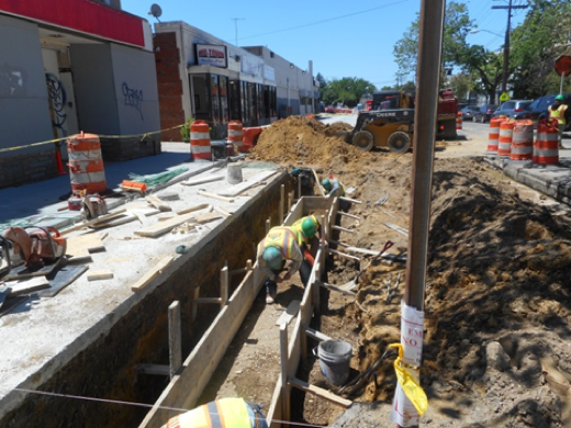 Forming footing for seat wall in front of building #116