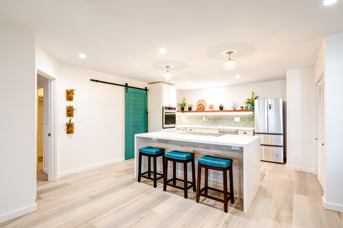 The living room flows into the open concept kitchen without barriers. We decided to go with a large island that has waterfall edges on both sides. The vinyl flooring goes up the backside of the island to give it some character.