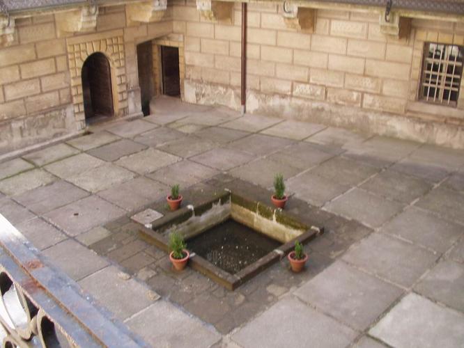 Shot of the center courtyard showing the drainage grate over the original fissure, filled in by rocks and concrete. Some believe it's a water well or fountain, but those who visit don't seem to think so. Photo by No. 666