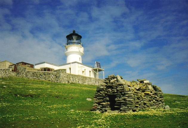 The lighthouse with the stone chapel built by St. Flannan in the 7th century in the foreground. Photo Credit By JJM, CC BY-SA 2.0