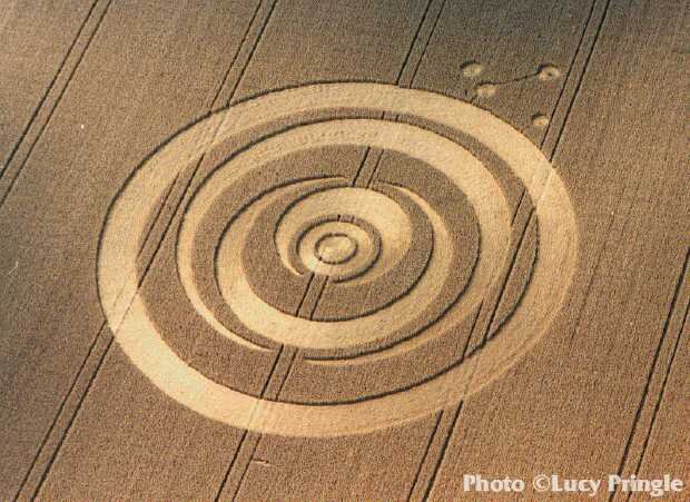  Henwood, Hampshire, mid-July 1995.  “Three nested crescents within a wide ring with two smaller rings within the inner crescent. Outside the formation lie four small grapeshot circles.”  Photo: © Lucy Pringle 1990 