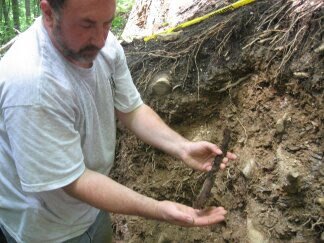  Frank Watson at a part of the archaeological excavation site and a victim they call SK003 
