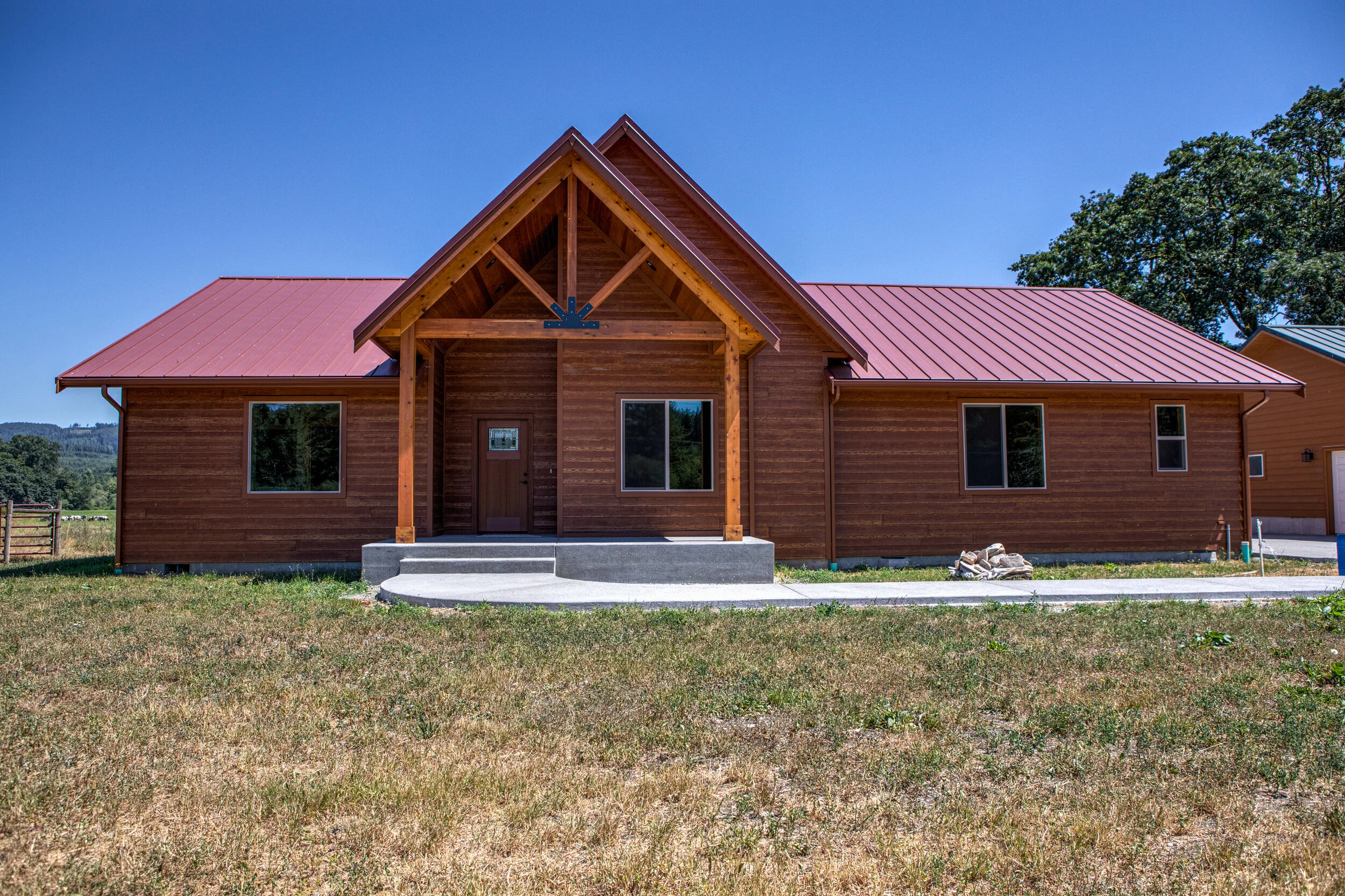 Gary's mountain-style custom home in Elma featuring log-inspired design with red metal roof - FoxHead Construction Grays Harbor County