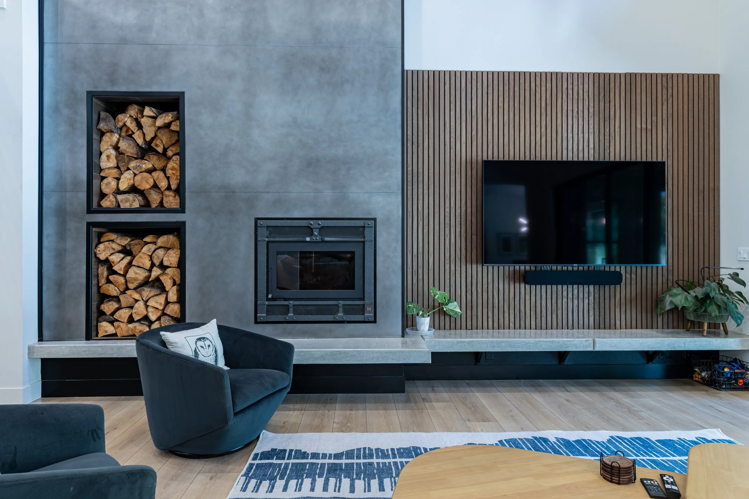 Troy's custom home built in Rainier featuring 2-story artisan faux concrete accent wall with fireplace and built-in firewood storage - FoxHead Construction Thurston County