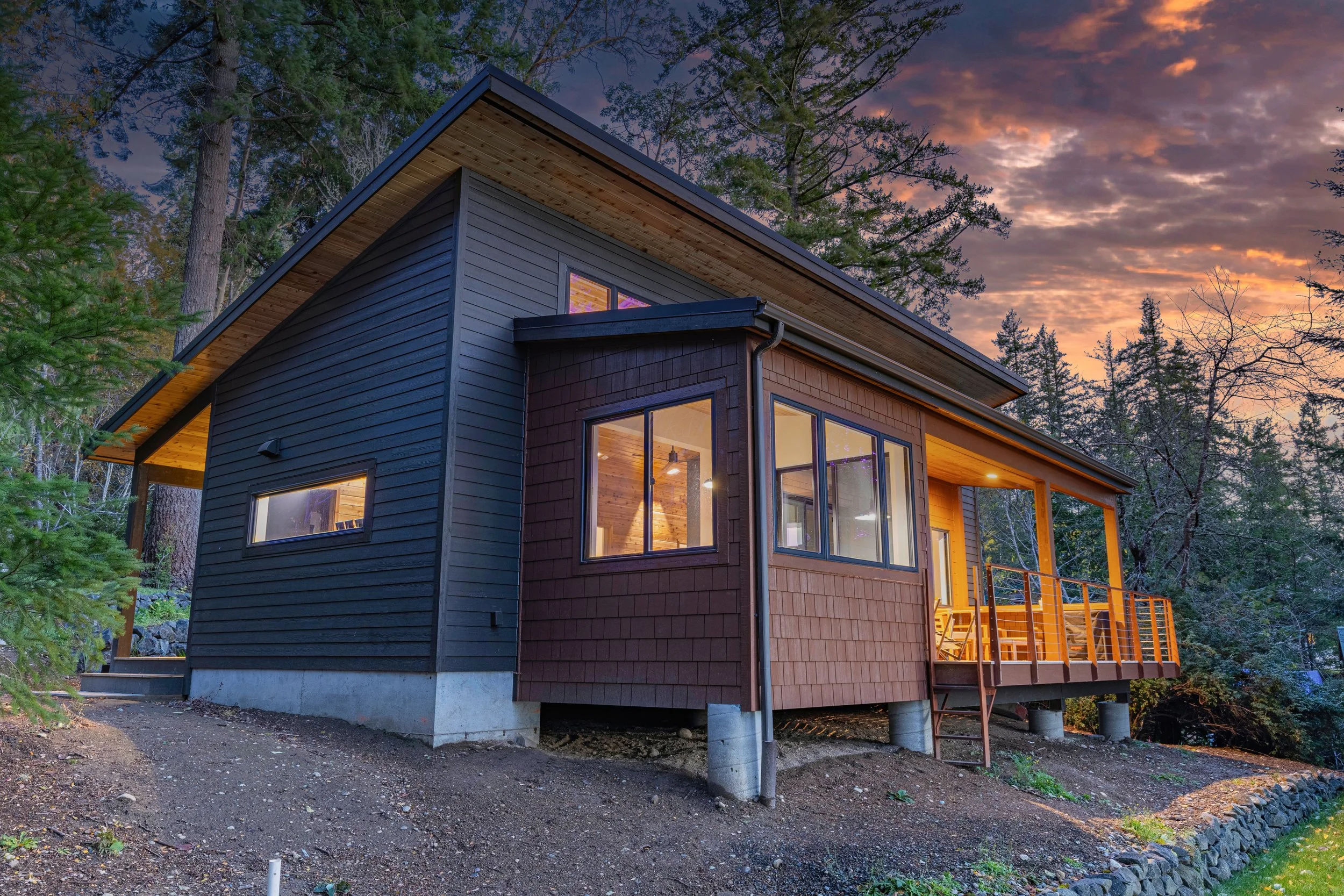 Contis' modern custom cabin on Harstine Island featuring natural wood exterior and covered deck - FoxHead Construction Mason County